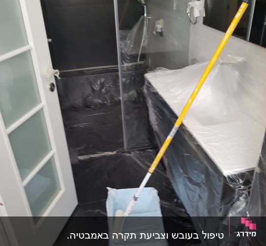 רולר צביעה ומגש בחדר מכוסה בניילון